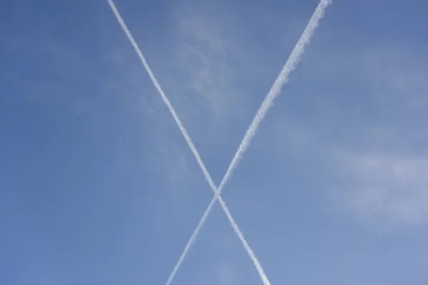 Formation in the sky of a big X with airplane contrails