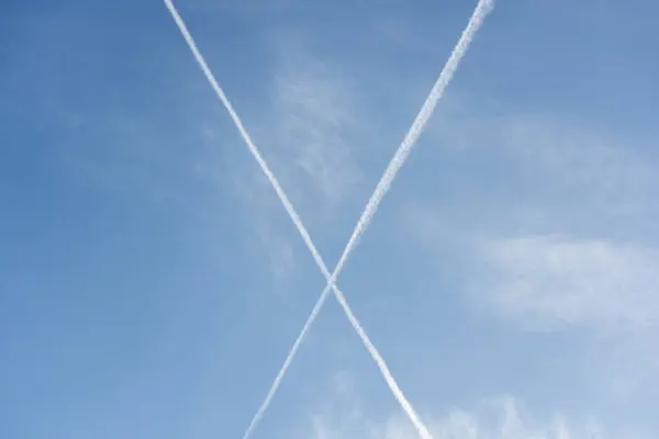 Formation in the sky of a big X with airplane contrails