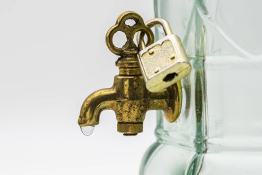 Bronz bir musluğun ayrıntıları, bir damla suyla, asma kilit ile kapatılmış, beyaz üzerine izole edilmiş.