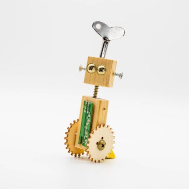 Tahtadan ve vidalardan yapılmış küçük bir robot. Kurma anahtarıyla, beyazın üzerinde izole edilmiş.