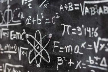 Mathematical operations and quantum physics formulas handwritten with a chalk on the blackboard clipart