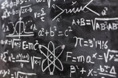 Matematiksel işlemler ve kuantum fiziği formülleri tahtaya tebeşirle yazılmış.