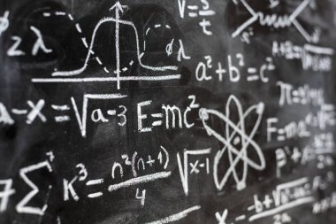 Matematiksel işlemler ve kuantum fiziği formülleri tahtaya tebeşirle yazılmış.