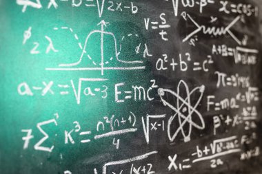 Mathematical operations and quantum physics formulas handwritten with a chalk on the blackboard clipart