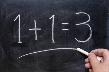 Bir artı bir eşittir üç. Tahtaya tebeşirle yazılmış.