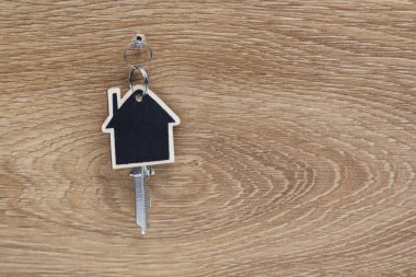 Anahtarı olan, duvarda asılı bir ev şeklinde tahta anahtarlık.
