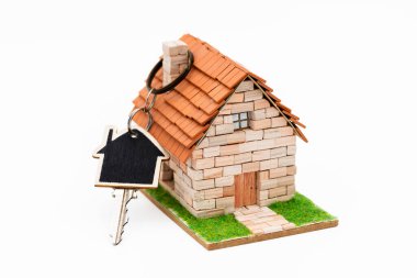 Anahtarı bacaya takılı minyatür bir ev, beyaza izole edilmiş.