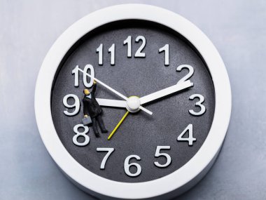 Saatin ellerinden sarkan minyatür bir adam figürü.