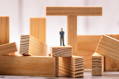 Tahta blokların üzerinde duran bir adamın minyatür figürü.