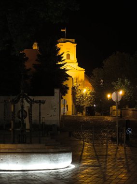 Macaristan 'ın Gyor kentindeki aydınlatılmış Bishop' s Castle 'ın dekoratif kuyusu ve tarihi binaları olan bir gece sahnesi. Sıcak sokak lambaları kaldırım taşı sokakları ve mimari ayrıntıları vurguluyor - 5 Mayıs 2018