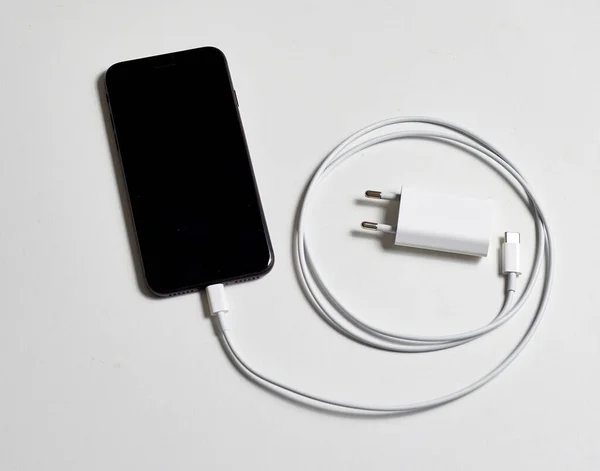 带电缆概念 能量和电池充电的黑色智能手机和白色充电器 — 图库照片
