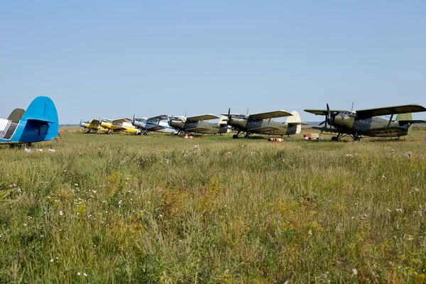 Planes in the distance are standing in a field around barrels of Lukoil fuel are lying on the grass.