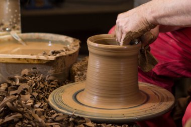 Çömlekçinin elleri çömlekçi çarkında kille çalışıyor, kâse oluşturuyor. Geleneksel çömlek, el sanatları, otantik atmosfer