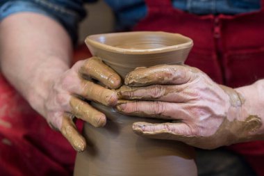 Çömlekçinin elleri çömlekçi çarkında kille çalışıyor, kâse oluşturuyor. Geleneksel çömlek, el sanatları, otantik atmosfer