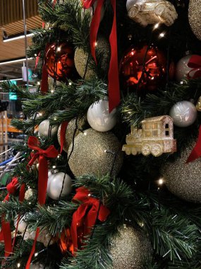 Fotoğraf birçok dekoratif unsurla süslenmiş bir Noel ağacını gösteriyor. Ağaç büyük altın, kırmızı ve beyaz topların yanı sıra kırmızı kurdelelerle süslenmiştir. Ağaçta evler ve diğer dekorasyon gibi küçük heykelcikler de bulunuyor.