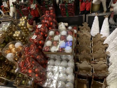 Fotoğrafta festival dekorasyonlu bir vitrin yer alıyor: koni ve böğürtlenli ahşap ağaçlar, Noel çelenkleri ve dekorlu şeffaf çantalar. Sahne, Noel ve Yeni Yıl atmosferini yakalıyor