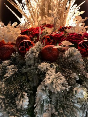 The photo features a decorative arrangement consisting of a large woven basket adorned with artificial pine branches with a snow effect, red flowers, and glittering balls. In the center of the arrangement, there are golden spikes and white decorative clipart