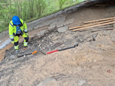 Köprü yenilenmesi ve modern bir inşaat sahasında kaldırım döşemesi sergilenen yüksek kaliteli bir fotoğraf. İşçiler aktif olarak yol çalışması yapıyor, şehir altyapısını geliştiriyorlar. Olay yerinde inşaat ekipmanları, malzemeler ve