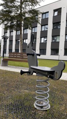 Modern bir çocuk parkına yerleştirilmiş tavşan şeklinde renkli bir yay binicisi. Güvenli açık hava oyunları ve fiziksel aktiviteler için tasarlanan bu araç gereç, küçük çocuklarda denge ve koordinasyon geliştirmeye yardımcı oluyor. Kamu parkında kullanmak için ideal