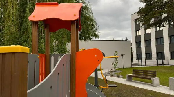 Renkli bir kaydırak, tırmanma merdiveni, küçük ahşap oyun evi ve köprü yapısı olan modern açık hava çocukları için oyun alanı. Kamu parkında ya da eğlence alanında geçen bu ekipman fiziksel aktiviteyi, hayal gücünü ve sosyal etkileşimi teşvik eder..