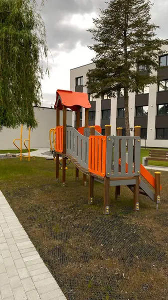 Renkli bir kaydırak, tırmanma merdiveni, küçük ahşap oyun evi ve köprü yapısı olan modern açık hava çocukları için oyun alanı. Kamu parkında ya da eğlence alanında geçen bu ekipman fiziksel aktiviteyi, hayal gücünü ve sosyal etkileşimi teşvik eder..