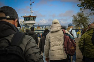 Güneşli bir günde Klaipeda 'da, arka planda su ve şehir bulunan bir nehir feribotundaki insanlar. Klaipeda, 93100 Klaipedos m. sav., Litvanya 05.03.2025: 14: 29. Yüksek kalite fotoğraf