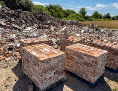 Eski kırmızı tuğlaların geri dönüşümü. Beton döküntüleri ve tuğlalar satılmaya hazır. Yeniden kullanılabilir yapı malzemeleri soyut.