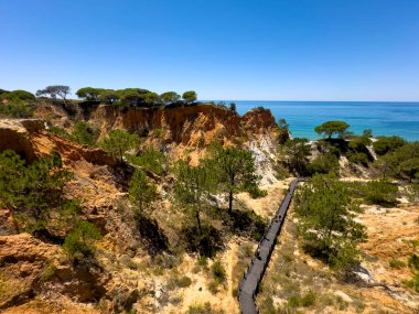 Portekiz 'in Albufeira bölgesine sahil ulaşımı. Olhos de Agua kasabası. Etkileyici uçurumlar ve insan ahşap yol yaptı..