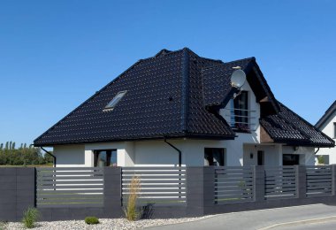 Polonya 'da siyah kiremit çatılı ve grafit çitli modern bekar aile evi. Çağdaş mimari soyut.