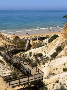 Portekiz 'in Albufeira bölgesine sahil ulaşımı. Olhos de Agua kasabası. Etkileyici uçurumlar ve insan ahşap yol yaptı..