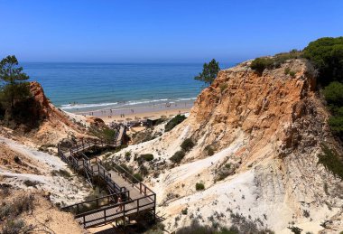 Portekiz 'in Albufeira bölgesine sahil ulaşımı. Olhos de Agua kasabası. Etkileyici uçurumlar ve insan ahşap yol yaptı..