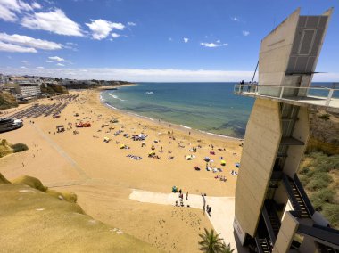 Albufeira, Portekiz, 26 Haziran 20024 - Güneşli bir yaz gününde şehrin ana sahil manzarası. Sahil girişi için asansör kulesi..