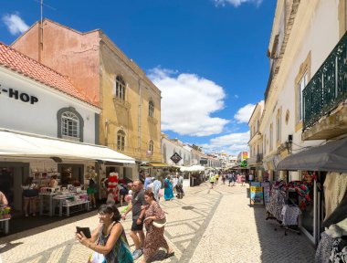Albufeira, Portekiz, 26 Haziran 2024 - yerel dükkanlar arasında turistlerin dolaştığı şehir merkezi dar cadde.