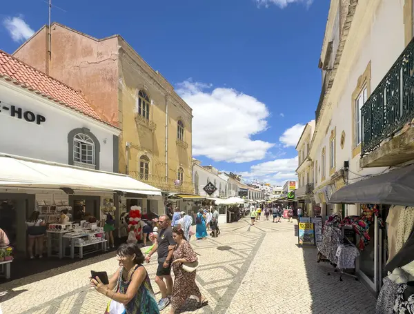 Albufeira, Portekiz, 26 Haziran 2024 - yerel dükkanlar arasında turistlerin dolaştığı şehir merkezi dar cadde.