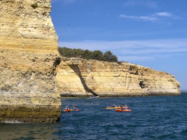 Albufeira, Portekiz, 26 Haziran 2024. Okyanustan görünen Algarve kıyılarının kayalıkları. İnsanlar manzaralı mağaraları keşfetmek için kanoya biniyor. Benagil mağarası..