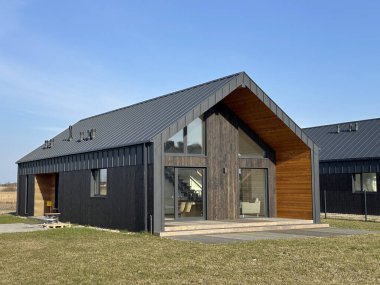 Görüntü, kırsal bir alanda yer alan parlak cam cepheli şık ve modern bir evi tasvir ediyor. Özenle tasarlanmış ortamlar cazibesini arttırır.