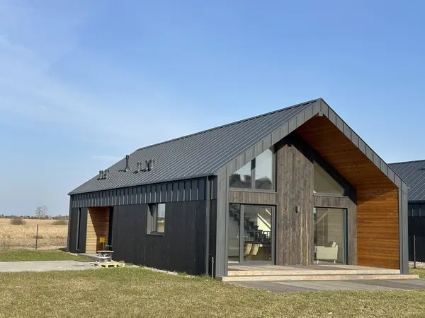 Görüntü, kırsal bir alanda yer alan parlak cam cepheli şık ve modern bir evi tasvir ediyor. Özenle tasarlanmış ortamlar cazibesini arttırır.