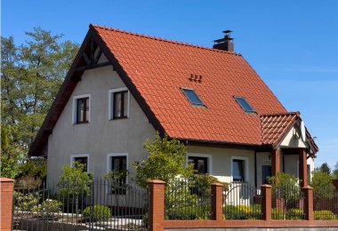 Kırmızı çatılı ve rahat bahçeli küçük bir banliyö evi. Gayrimenkul konsepti.