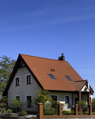 Kırmızı çatılı ve rahat bahçeli küçük bir banliyö evi. Gayrimenkul konsepti.