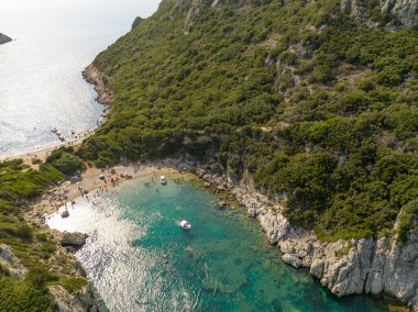 Yunanistan 'ın Korfu adasındaki Porto Timoni plajına giden kıyı şeridinin havadan görüntüsü. Kristal berrak sularla yıkanmış iki kumsal oluşturan ince bir şerit..
