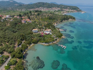 Aerial view of Notos Beach, Corfu Island. Greece. Bathers immersed in the crystal clear waters of the Greek coast. Coastline and houses and villas 