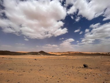 Merzouga, Erg Chebbi dunes, Morocco, Africa: panoramic road in the Sahara desert in the Black Mountain area, with view of the black stones, fossils and sand dunes, 4x4 trip, blue sky and white clouds