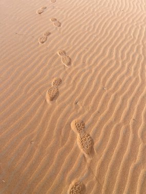 Sahra Çölü, Merzouga 'da bir kum tepesinde ayakkabı izleri. Kum tepelerinde küçük dalgalar oluşturan kum taneleri. Güneş batıyor. Fas