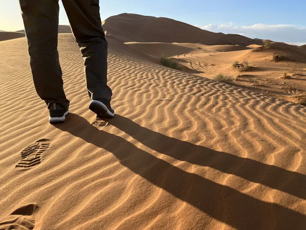 Shoe prints on a sand dune in the Sahara Desert, Merzouga. Grains of sand forming small waves on the dunes. Setting sun. Morocco