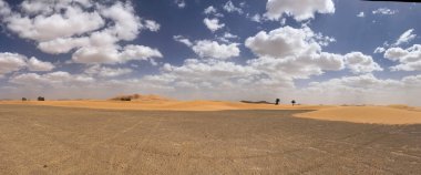 Merzouga, Erg Chebbi dunes, Morocco, Africa, panoramic road in the Sahara desert with view of the beautiful sand dunes and palm trees, 4x4 trip, blue sky and white clouds