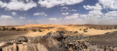 Merzouga, Erg Chebbi dunes, Morocco, Africa, panoramic road in the Sahara desert with view of the beautiful sand dunes, palm trees and tented camps, 4x4 trip, blue sky and white clouds