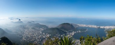 Rio de Janeiro, Brezilya, 06-07-2023: Sabah sisli gökyüzü manzarası ile Corcovado Dağı 'ndaki Kurtarıcı İsa' dan Sugarloaf Dağı, Copacabana plajı ve lagün ile görülüyor.