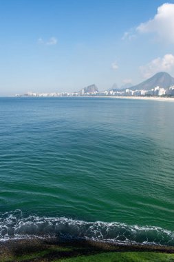 Rio de Janeiro, Brezilya, 06-07-2023: Gökdelenler ve Leme sahilinin kristal suyu ile şehrin panoramik manzarası Pedra do Leme (Leme Kayası), bitki örtüsüyle dolu kayalık bir tepe