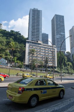 Rio de Janeiro, Brezilya, Güney Amerika, 06-07-2023: Botafogo bölgesinde trafiği yoğun bir cadde olan Avenida Lauro Sodr boyunca gökdelenleri, yağmur ormanları ve taksi bulunan şehir silueti