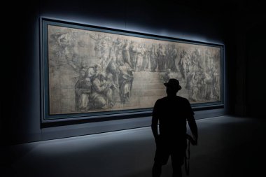 İtalya 'nın Milano kentindeki Ambrosiana Kütüphanesi' nde bulunan Raphael 'in Atina Okulu' nun hazırlık karikatürüne hayran kalan bir ziyaretçinin arka ışıklandırılmış silueti..
